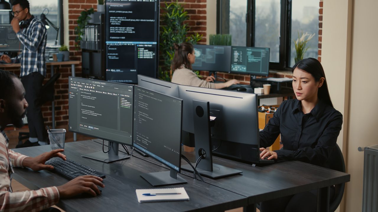 Two focused coders facing each other writing code in software development office